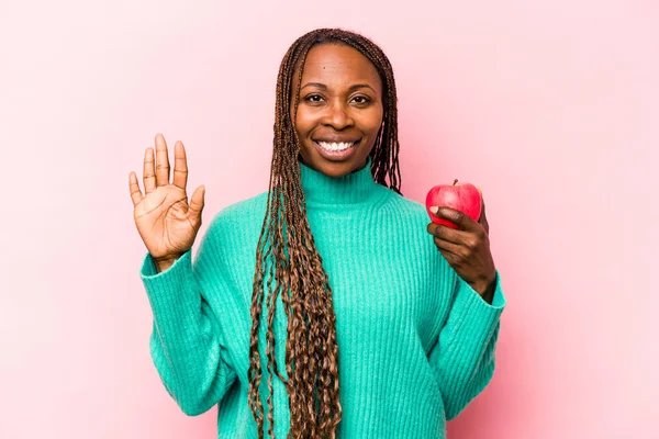 Ung Afroamerikansk Kvinna Håller Ett Äpple Isolerat Rosa Bakgrund Ler — Stockfoto