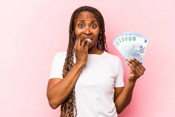 Молодая Афроамериканка Держащая Банкноты Розовом Фоне Кусает Ногти Нервничает Беспокоится — стоковое фото