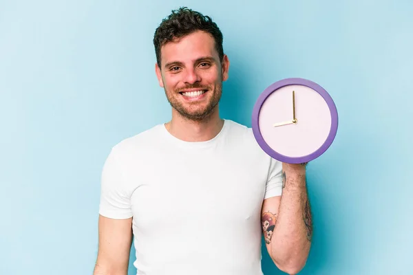 Young Caucasian Man Holding Clock Isolated Blue Background Happy Smiling — Stock Fotó