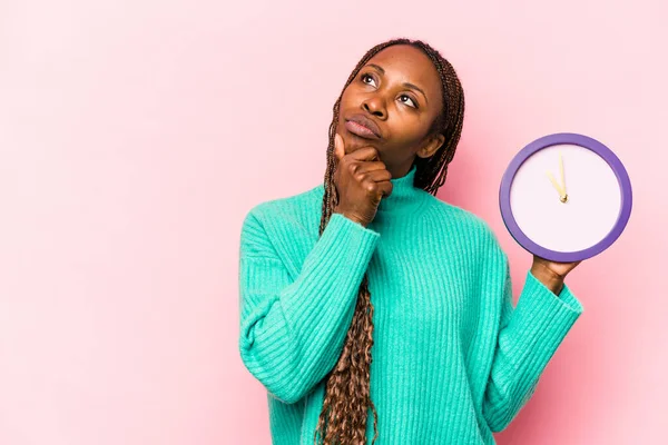 Ung Afroamerikansk Kvinna Som Håller Klocka Isolerad Rosa Bakgrund Tittar — Stockfoto