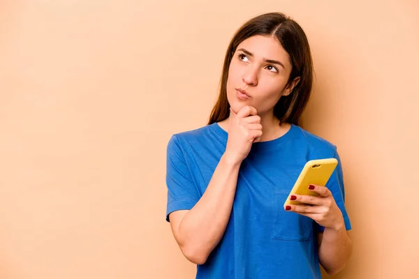Mladá Běloška Drží Mobilní Telefon Izolovaný Béžovém Pozadí Dívá Stranou — Stock fotografie