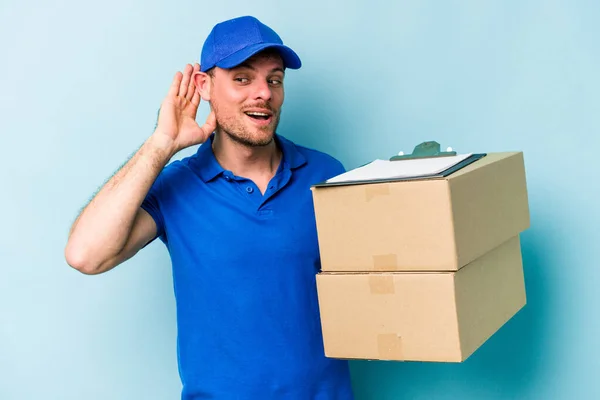 Young Caucasian Delivery Man Isolated Blue Background Trying Listening Gossip — Foto de Stock