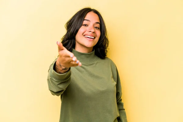 Young Hispanic Woman Isolated Yellow Background Stretching Hand Camera Greeting — 스톡 사진