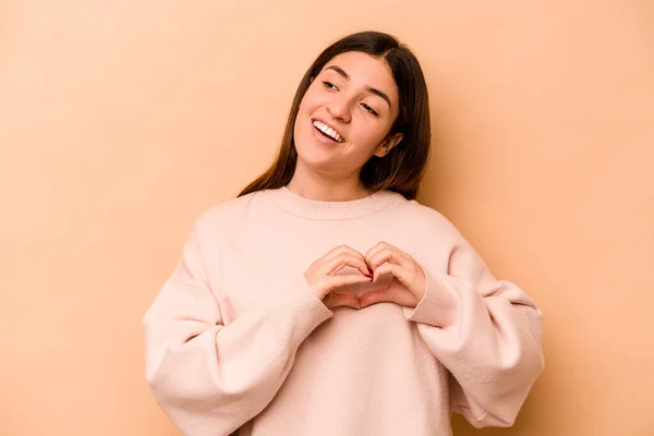 Jonge Spaanse Vrouw Geïsoleerd Beige Achtergrond Glimlachen Tonen Een Hart — Stockfoto