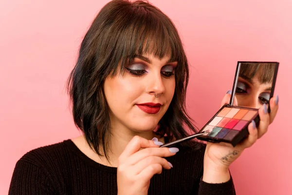 Pembe arka planda göz farı tutan beyaz bir kadın.