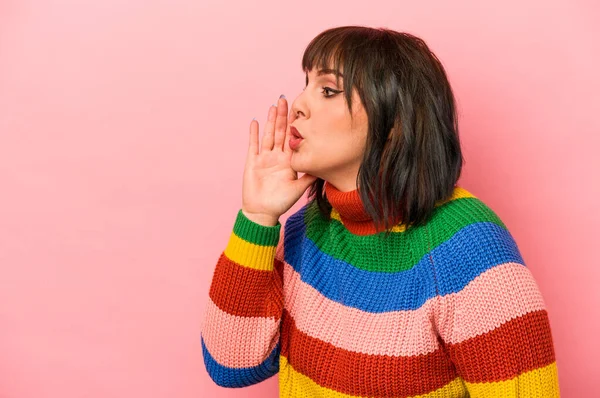 Pembe arka planda izole edilmiş genç beyaz kadın gizli bir sıcak fren haberi veriyor ve yana bakıyor.