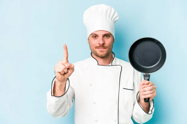 年轻的高加索厨师拿着用蓝色背景隔开的飞盘 带着第一指尖 — 图库照片