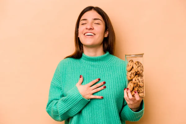 Молода Іспаномовна Жінка Тримає Банку Печива Ізольовано Бежевому Фоні Сміється — стокове фото