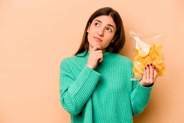 Jonge Spaanse Vrouw Met Een Zak Chips Geïsoleerd Beige Achtergrond — Stockfoto