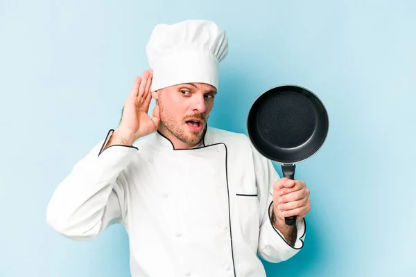 年轻的高加索厨师拿着一只被蓝色背景隔离的飞碟 想听一些闲话 — 图库照片