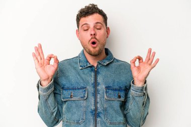 Beyaz arka planda izole edilmiş genç beyaz adam yoğun bir günün ardından rahatlıyor. Yoga yapıyor..