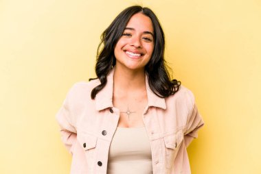 Sarı arka planda izole edilmiş genç İspanyol kadın mutlu, güler yüzlü ve neşeli.