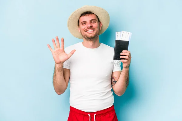 青い背景に孤立したパスポートを持っている若い白人旅行者の男笑顔陽気なショー番号5とともに指 — ストック写真
