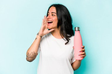 Mavi arka planda termo tutan genç İspanyol kadın bağırıyor ve avuç içini açık tutuyor..