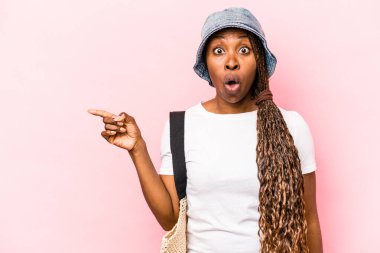 Genç Afrikalı Amerikalı bir kadın kumsala gidiyor. Pembe arka planda izole edilmiş.