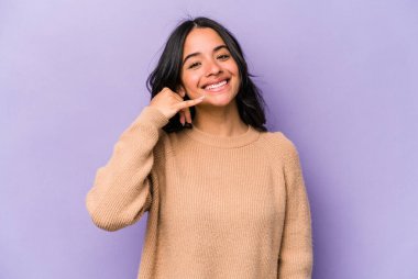 Mor arka planda izole edilmiş genç İspanyol kadın parmaklarıyla bir cep telefonu hareketi gösteriyor..