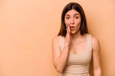 Latin kökenli genç bir kadın, bej arka planda izole edilmiş bir şekilde gizli bir sıcak fren haberi veriyor.