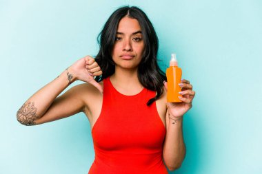 Mavi arka planda güneş kremi tutan genç İspanyol kadın hoşlanmadığı bir hareket sergiliyor. Anlaşmazlık konsepti.