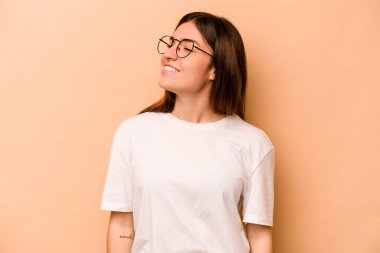 Latin kökenli genç bir kadın, bej arka planda izole edilmiş, gevşemiş ve mutlu bir şekilde gülüyor, boynunda diş izleri var..