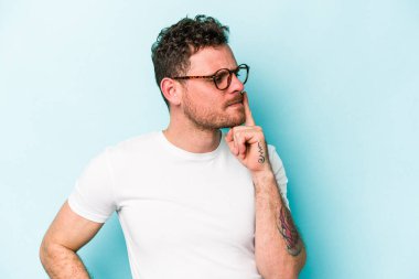 Mavi arka planda izole edilmiş genç beyaz bir adam ya sır saklıyor ya da sessizlik istiyor..