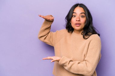 Mor arka planda izole edilmiş genç İspanyol kadın elleri arasında bir kopya alanı tutarken şok ve hayrete düştü..