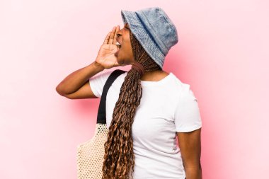 Genç Afrikalı Amerikalı kadın plaja gidiyor. Pembe arka planda izole edilmiş. Bağırıyor ve avuç içini açık tutuyor..