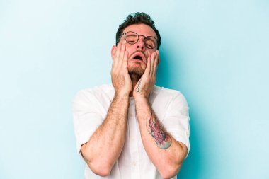 Kafkasyalı genç adam mavi arka planda izole edilmiş sızlanıyor ve ağlıyordu..