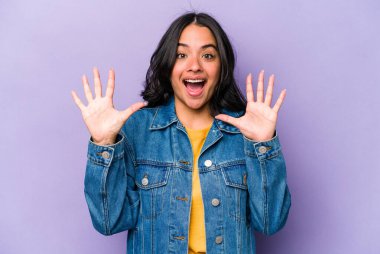 Mor arka planda izole edilmiş genç İspanyol kadın hoş bir sürprizle karşılaşıyor, heyecanlı ve el kaldırıyor..
