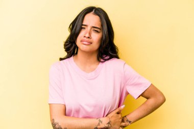 Sarı arka planda karaciğer ağrısı çeken, karnı ağrıyan genç bir İspanyol kadın..