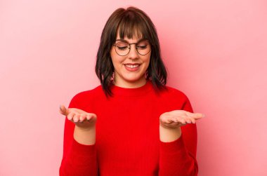 Pembe arka planda izole edilmiş beyaz bir kadın elinde avuç içi bir şeyle kameraya sunuyor..