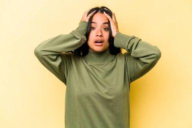 Sarı arka planda izole edilmiş genç İspanyol kadın şaşırdı ve şok oldu..