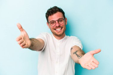 Mavi arka planda izole edilmiş beyaz bir genç hoş bir yüz ifadesi sergiliyor..