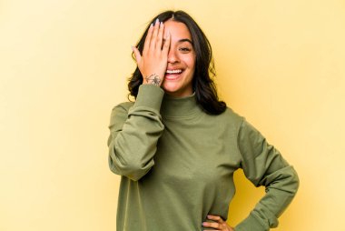 Sarı arka planda izole edilmiş genç İspanyol kadın yüzünün yarısını palmiye ile örterek eğleniyor..