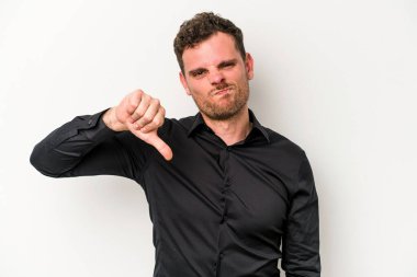 Beyaz arka planda izole edilmiş genç beyaz bir adam baş parmağını aşağı gösteriyor ve hoşlanmadığını ifade ediyor..