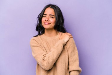 Mor arka planda izole edilmiş genç İspanyol kadın omuz ağrısı çekiyor..