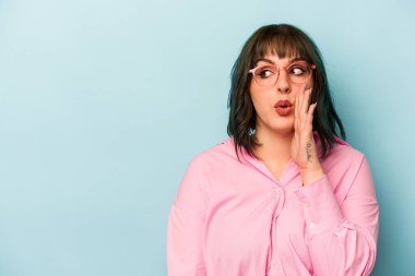 Mavi arka planda izole edilmiş genç beyaz kadın gizli bir sıcak fren haberi veriyor ve yana bakıyor.