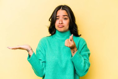 Sarı arka planda izole edilmiş genç İspanyol kadın parası olmadığını gösteriyor..