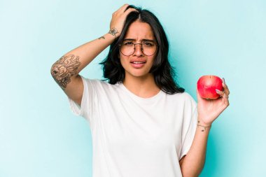 Mavi arka planda izole edilmiş bir elma tutan genç İspanyol kadın şok geçiriyordu, önemli bir toplantıyı hatırladı..