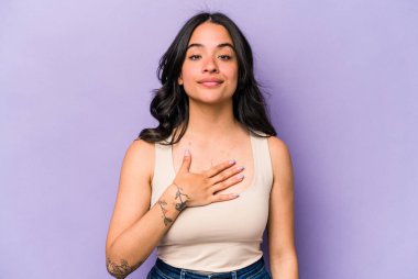 Mor arka planda izole edilmiş genç İspanyol kadın yemin ediyor, elini göğsüne koyuyor..