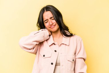 Sarı arka planda izole edilmiş genç bir İspanyol kadın sabit yaşam tarzından dolayı boyun ağrısı çekiyor..