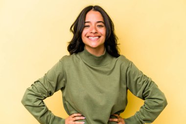 Sarı arka planda izole edilmiş genç İspanyol kadın mutlu, güler yüzlü ve neşeli.