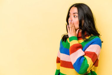 Sarı arka planda izole edilmiş genç İspanyol kadın gördüğü bir şey yüzünden şoka uğruyor..