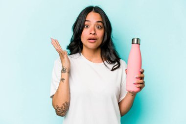 Mavi arka planda termo tutan genç İspanyol kadın şaşırdı ve şok oldu..