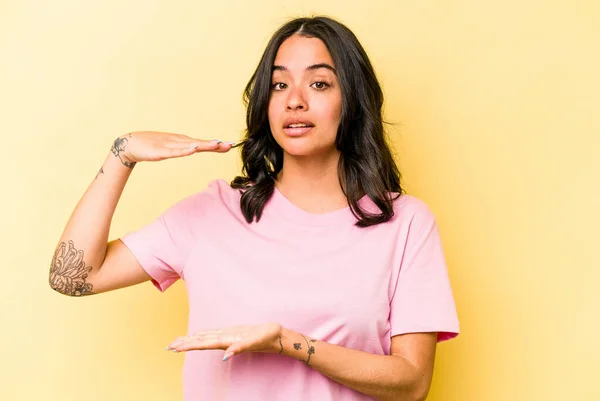 Young Hispanic Woman Isolated Yellow Background Holding Something Both Hands — 스톡 사진