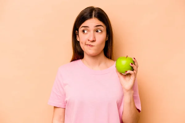 Junge Hispanische Frau Hält Einen Apfel Isoliert Auf Beigem Hintergrund — Stockfoto