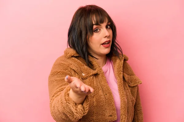 Pembe arka planda izole edilmiş beyaz bir kadın. Kameraya elini uzatıp selam veriyor..