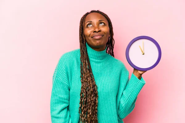 Ung Afroamerikansk Kvinna Som Håller Klocka Isolerad Rosa Bakgrund Drömmer — Stockfoto