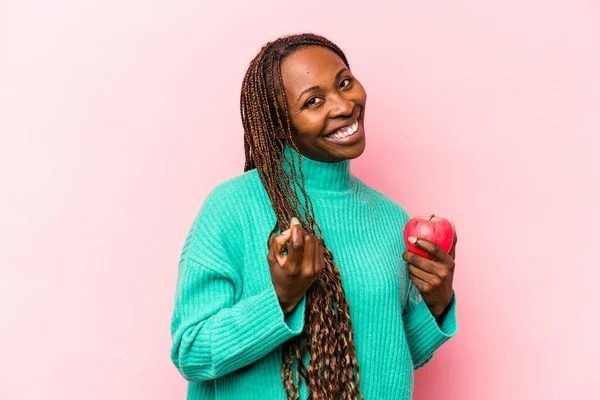 年轻的非洲裔美国女人拿着一个粉色背景的苹果 用手指指着你 好像邀请你走近些 — 图库照片