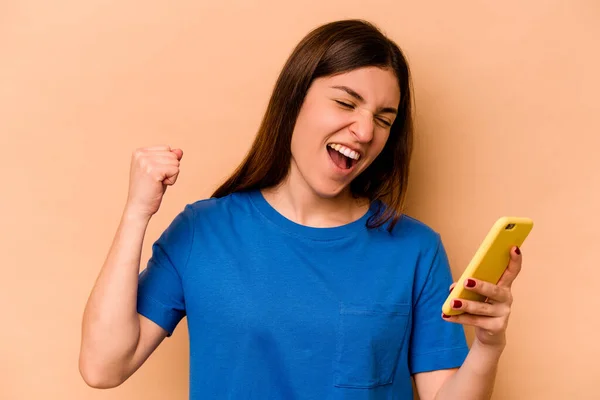 Joven Mujer Caucásica Sosteniendo Teléfono Móvil Aislado Sobre Fondo Beige —  Fotos de Stock