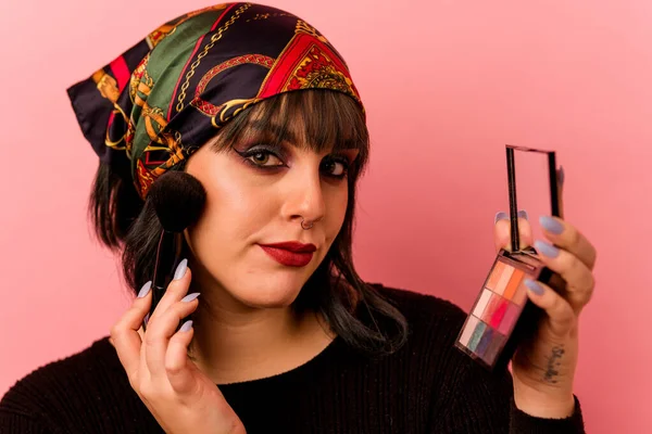 Pembe arka planda göz farı tutan beyaz bir kadın.